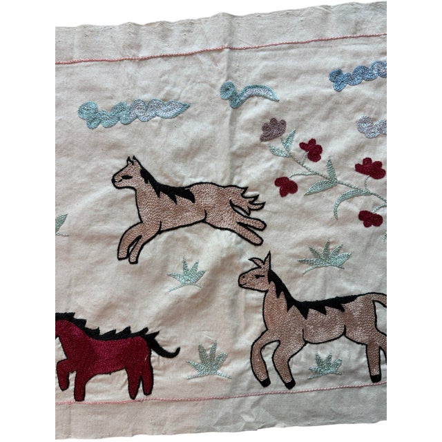 Hand-embroidered Suzani panel from Uzbekistan, worked in fine floss on a cream cotton ground. Six horses move across the...