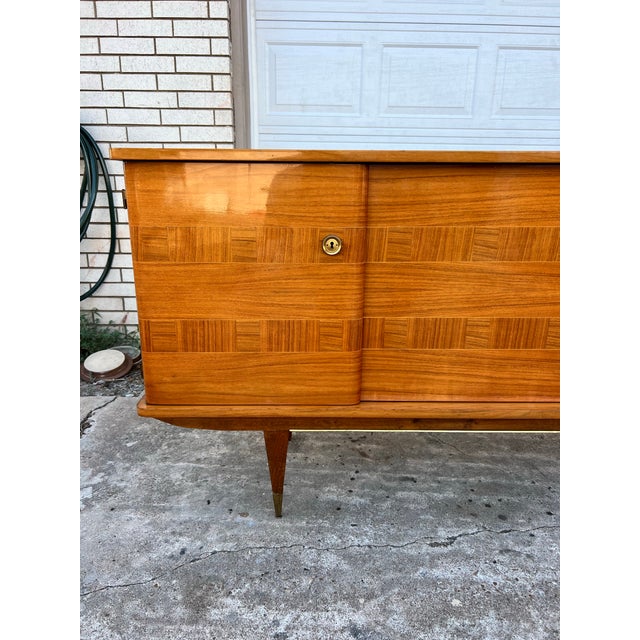 Elegant French Art Deco sideboard dating to circa 1950, featuring a beautifully figured warm-toned wood façade with...