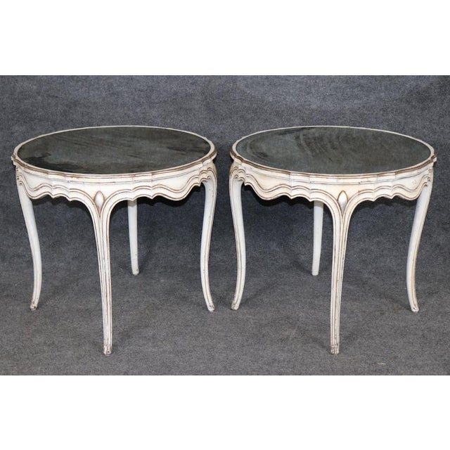 An exquisite and highly decorative pair of French Louis XV-style painted and gilded marble-top side tables, dating to the...