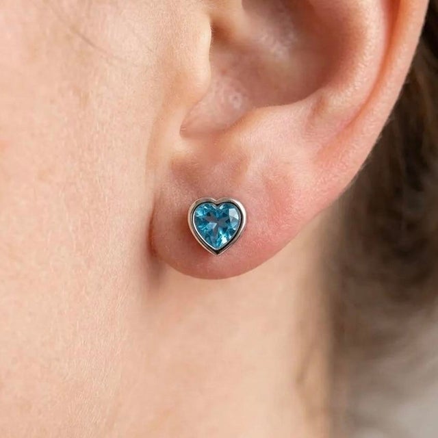 These charming stud earrings feature vibrant Blue Topaz gemstones, admired for their brilliant sky-blue color and...