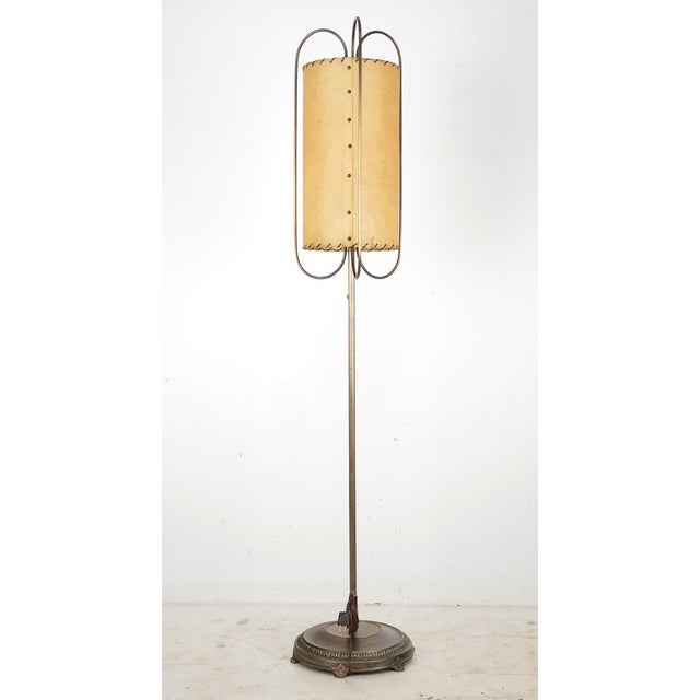 Mid Century Modern floor lamp with an elongated shade with stitching at the ends and a weighted brass finished base. This...