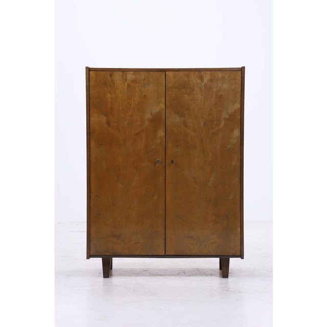Vintage linen cupboard from the 1960s with clean lines and beautiful wood grain. The combination of shelves and three...