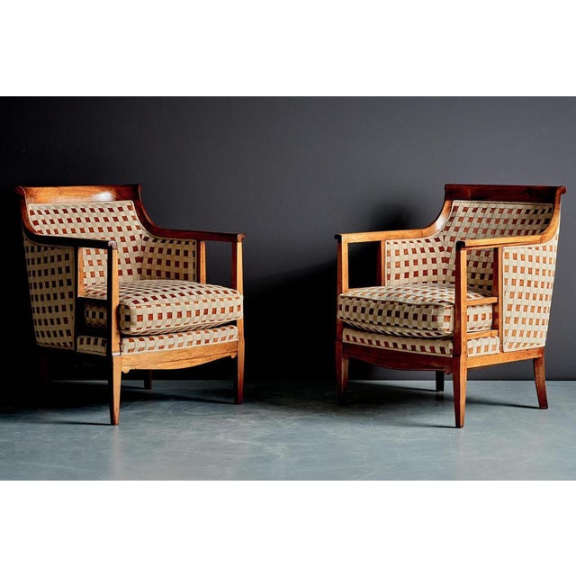 A refined pair of Art Deco lounge chairs with sculptural wooden frames and gently curved backs. The design combines strong...