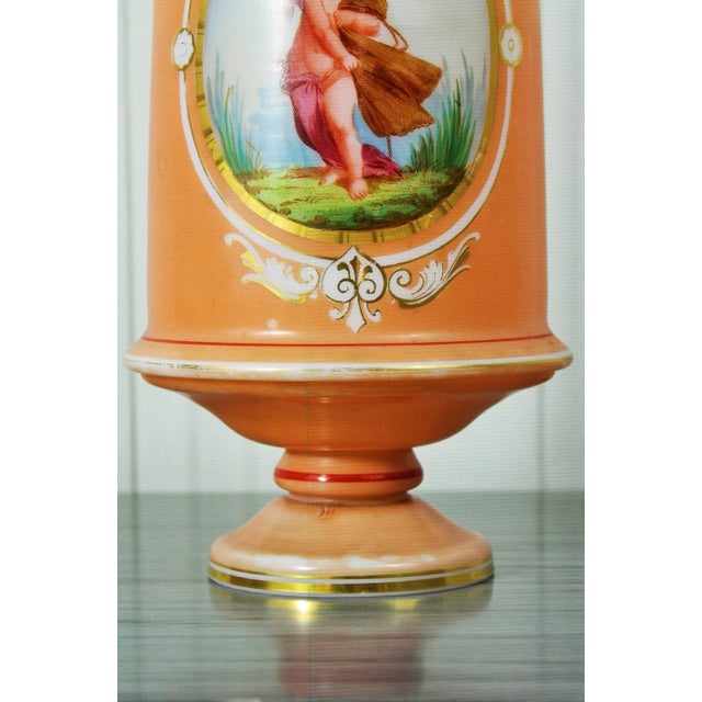 Charming vase in opaline glass, painted and gilded, with a reserve in which is represented a cherub bearing a laundry....