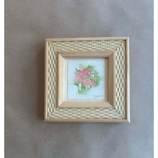 Delicate and airy, this original watercolor captures a loose bouquet of pink blossoms with soft green washes, rendered in...