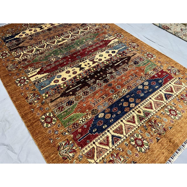 This beautiful Persian-style tribal area rug features a warm brown background with colorful geometric stripes and...
