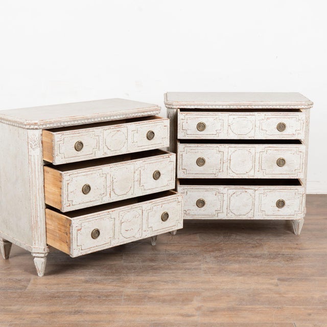 Pair of 20th century Danish chests of three drawers, crafted in pine. Carved dental molding accents the top, while lovely...