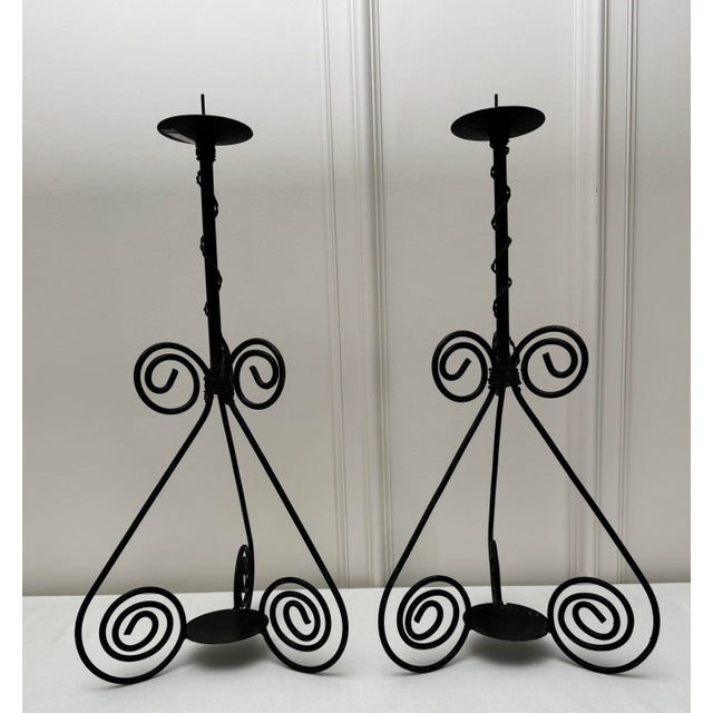 A pair of Spanish inspired to Abstract Modern styled black iron metal candle holders fit one pillar candle each. The...