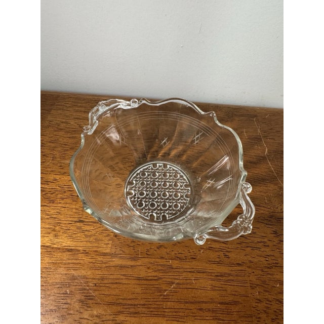 Vintage clear pressed glass serving bowl featuring decorative double handles, etched accents, and a geometric pressed-...
