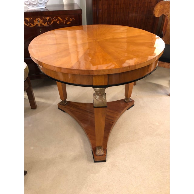 A fine Biedermeier center table. Cherrywood with ebonized fruitwood details and carved giltwood caryatids. Full...