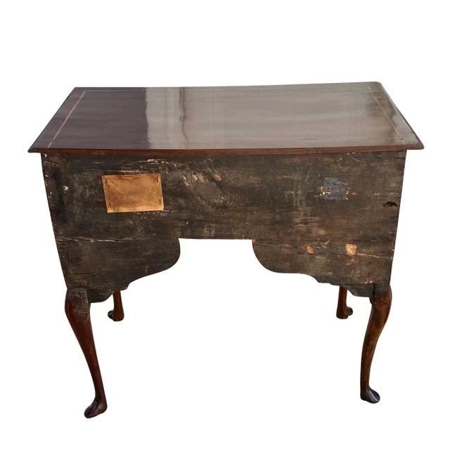 A fine early 18th century English Queen Anne walnut lowboy. The rectangular molded top is decorated with a line inlay. The...