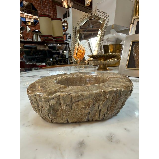 A substantial marble ashtray featuring rich brown, taupe, and cream natural veining. Its irregular, organic shape and...