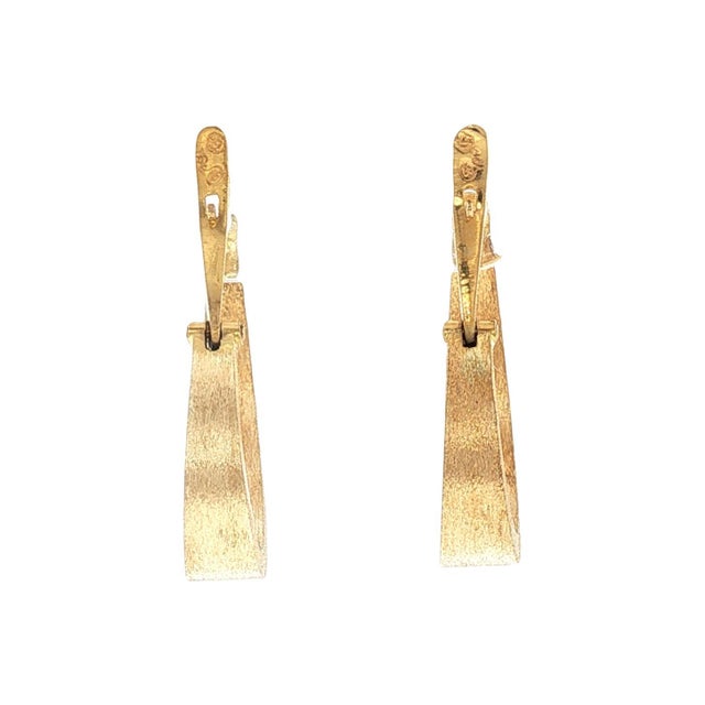 A pair of late 20th-century hoop earrings crafted from 18k gold. The design features a sleek, elongated form with a subtle...