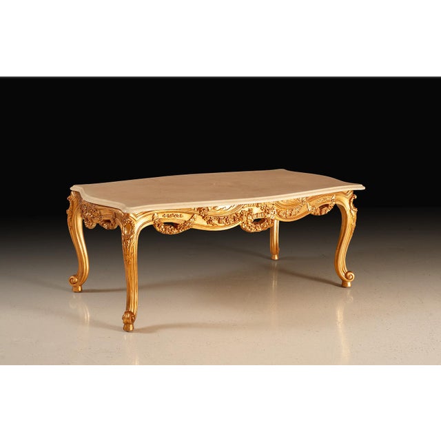 Coffee table richly adorned with a hand-applied 24-karat gold leaf finish that highlights every curve and carving. The...