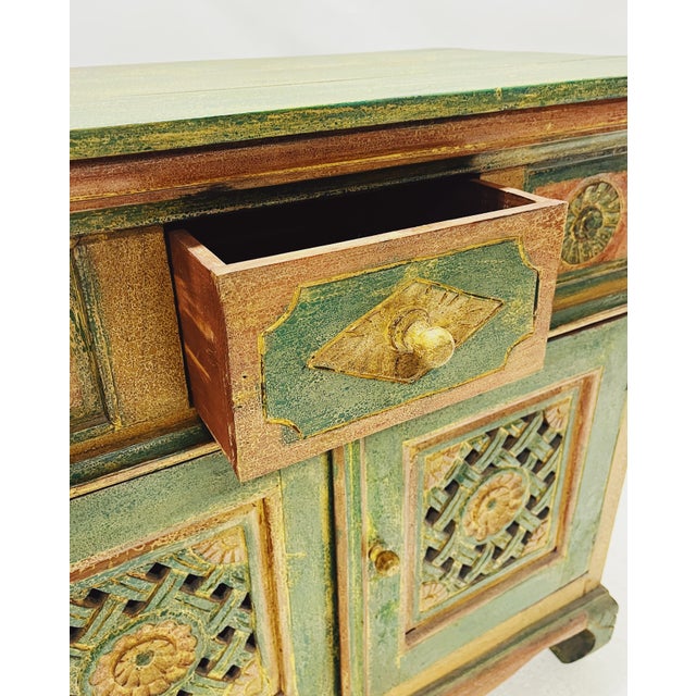 This vintage/antique cabinet likely originates from India. The cabinet is hand-painted in green and orange and features...