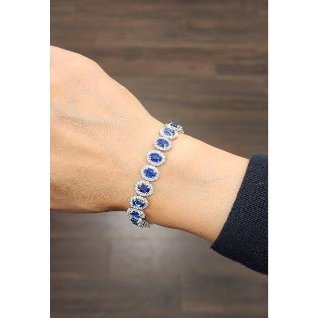 A modern tennis bracelet crafted in platinum, featuring 22.1 carats of 22 natural oval blue sapphires and 4.14 carats of...