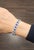 A modern tennis bracelet crafted in platinum, featuring 22.1 carats of 22 natural oval blue sapphires and 4.14 carats of...