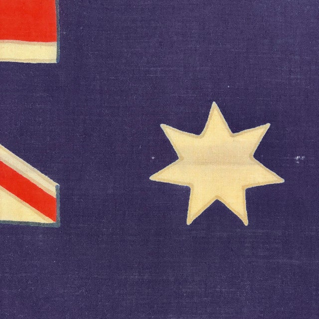 This vintage Australian flag is made from a coarse woolen cloth in faded violet blue, warm off-white, and vibrant orange...