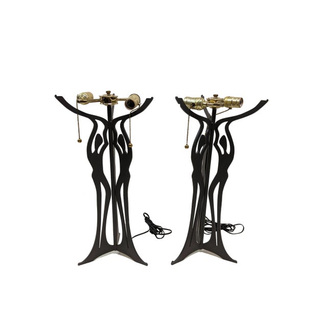 A pair of metal and glass three graces table lamps by Cricket Forge. The handcrafted steel base displays the three graces...
