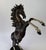 A striking bronze sculpture of a rearing horse, captured mid-motion in a powerful, elevated stance. This prancing stallion...