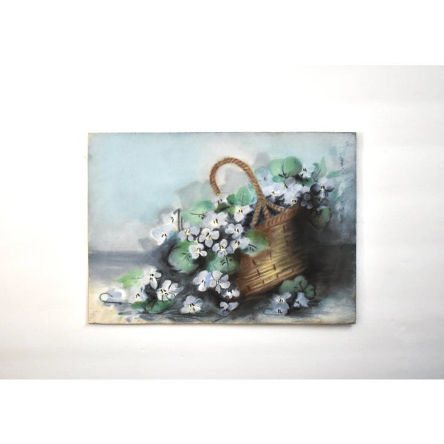 An antique pastel still life of a basket overflowing with flowers, blue violets. Chalk pastel on cardboard, early- to...