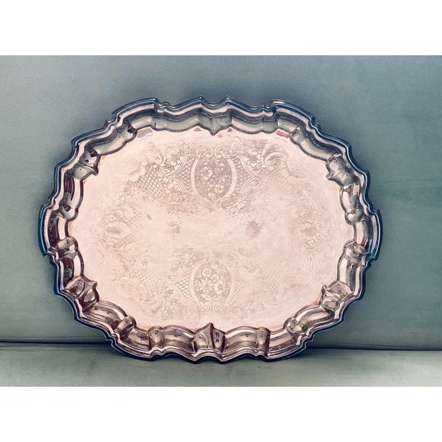 An elaborately etched tray in a floral pattern with a baroque style scalloped edge on four small feet.