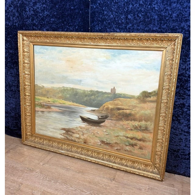 A. Monier 1906: Oil on canvas "Lakeside Landscape" / 112 x 140 cm. Boats beached on the riverbank with a castle tower on a...