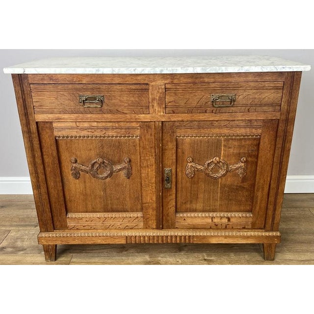 This elegant Antique French cabinet is crafted from oak and features a beautiful marble top, carved decorative panels, and...
