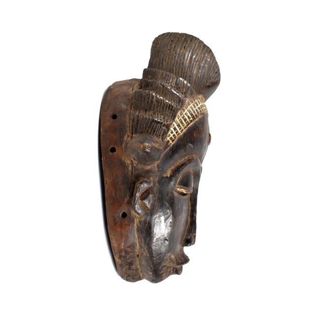 The Baule portrait mask discussed is intricately crafted for the Mblo dance, representing an honored person or ancestor in...
