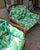 Vintage pair of bamboo lounge chairs with custom upholstery outside inside tropical banana leaves.