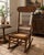 Beautiful vintage solid oak rocking chair featuring an intricately hand-carved crest rail, turned spindle back, and woven...