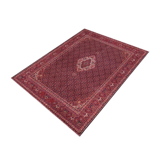 A beautiful hand-knotted wool rug measuring approximately 10'0" x 12'6". This large room-size carpet features a deep blue...