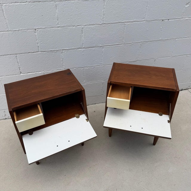 Pair of walnut “Dania” nightstands by American of Martinsville. Clean-lined walnut cases with softly tapered legs, warm...