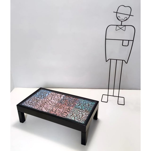Made in Italy, 1980s This coffee table is made black lacquered beech and features a hand-painted colorful plaster low...