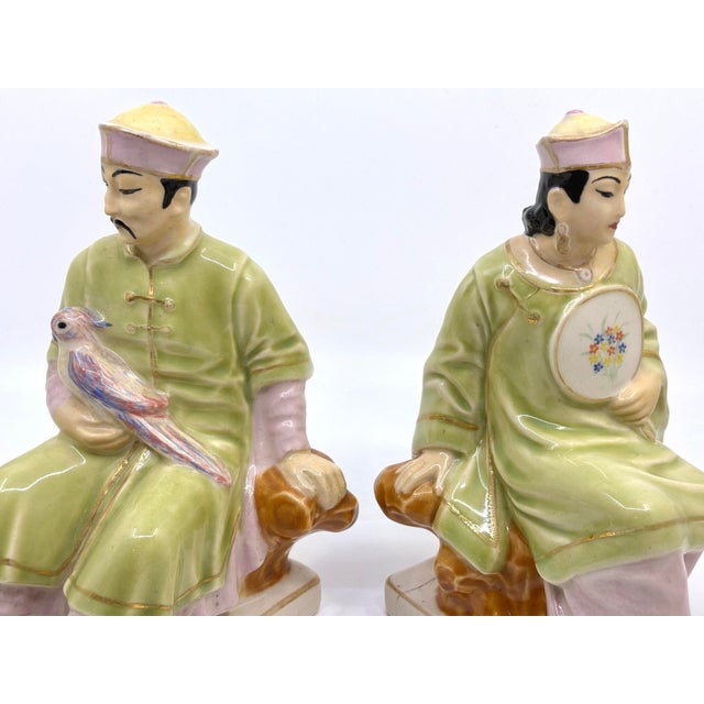 Vintage ceramic bookends or decorative figurines. Asian man holding a parrot and woman figure holding a floral fan....