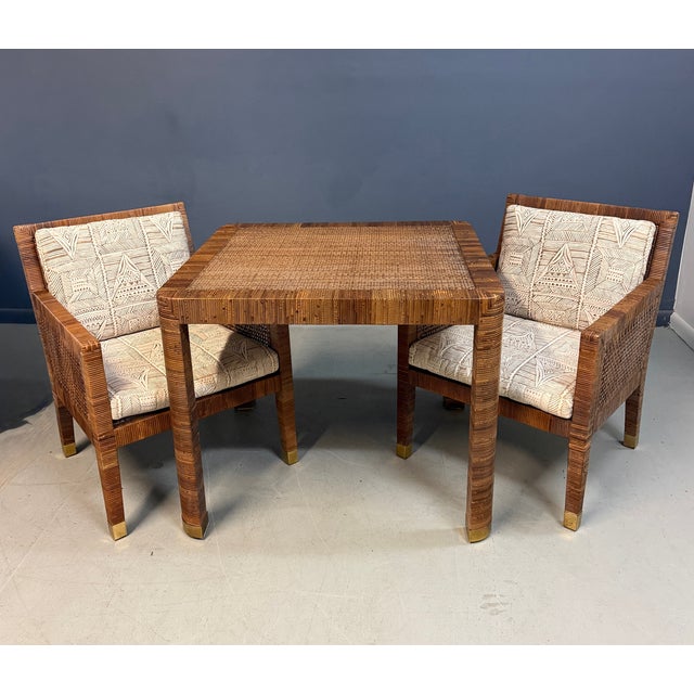 A chic rattan game table and pair of matching lounge chairs, designed by Billy Baldwin for Bielecky Brothers. The set...