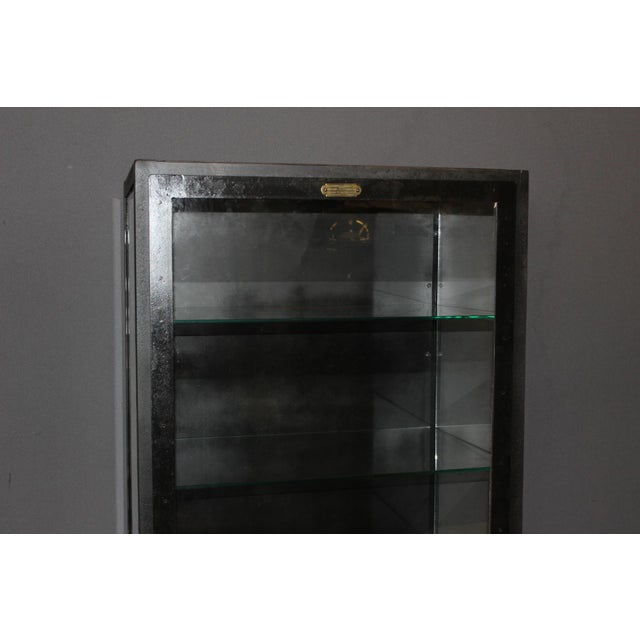 Iron and glass medicine display case, black patina, four shelves, it opens with a door, circa 1940, overall in very good...