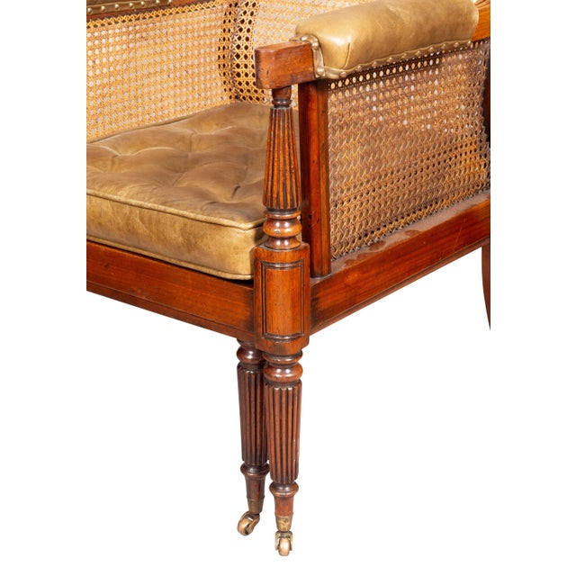 With straight molded crestrail over a caned back and sides, the arms with leather arm pads, tufted green leather seat...