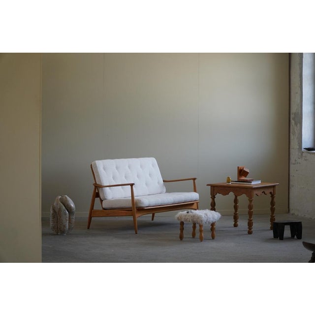 A fine example of a danish modern 2-seater sofa in solid beech, reupholstered cushions in white bouclé. Designed by arne...