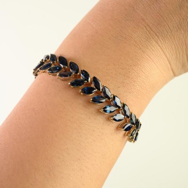 This elegant link bracelet features 62 marquise-cut natural blue sapphires totaling 29.19 carats, set in rich 14K yellow...