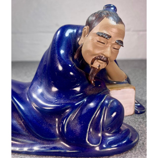 Detailed depiction of a Chinese scholar/sage resting wearing a deep navy blue colored wrobe.