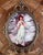 This is a vintage reproduction of Thomas Gainsborough’s “Pinkie,” displayed beneath convex glass in an ornate brass-tone...