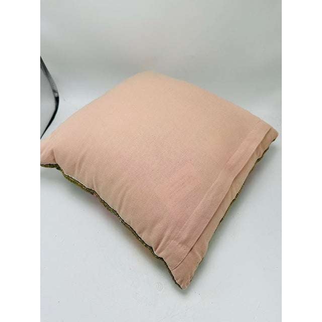 A decorative hand-beaded accent pillow featuring a pink flamingo surrounded by colorful flowers and leafy greenery. The...