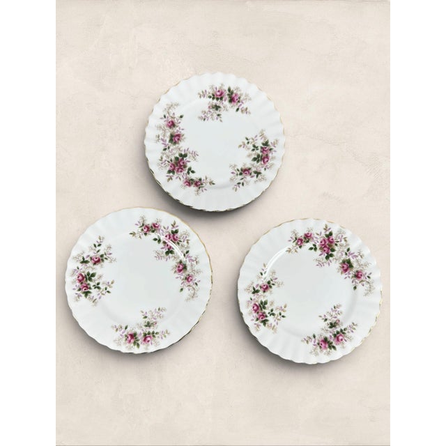 A beautiful set of three English fine bone china dessert plates by Roslyn, featuring delicate pink rose garlands accented...