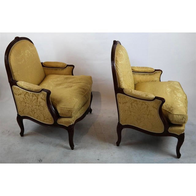 Pair of Louis XV Style gold upholstered down cushion bergeres, each with carved crest and apron. 38” H × 30” W x 24” D...