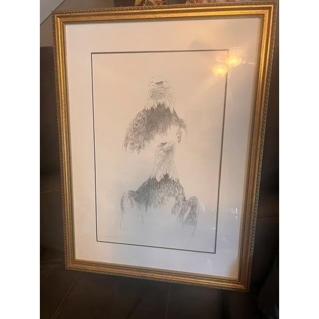 This framed fine art print features a detailed pencil sketch of two bald eagles, characterized by their expressive,...