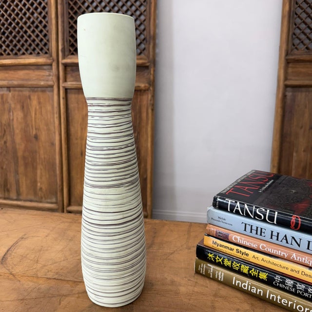 "About This Piece About This Piece Elegant and understated, this tall vase captures attention with its sleek form and...