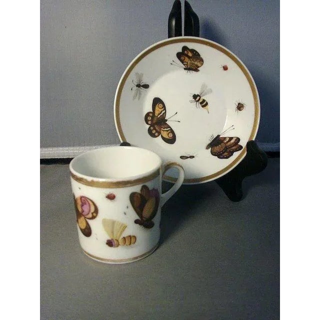 Antique Paris porcelain coffee can and saucer profusely decorated with bugs and butterflies in all stages of maturation....