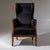 Biedermeier wingback armchair featuring a polished walnut frame on brass casters. The armrests rest on curved supports...