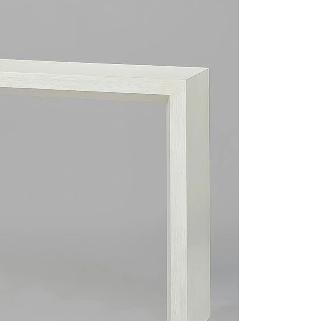 Modern painted console table with a beveled shape on the inside legs and lower side of the top, and a “drift” white...